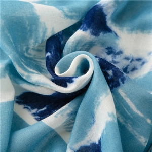 Close-up of soft blue and white tie-dye cotton linen scarf with wavy artistic texture