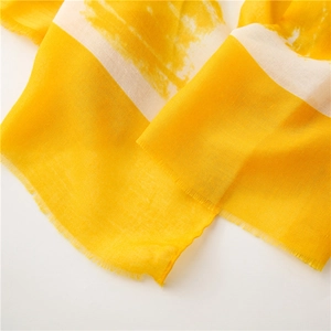 Detail of abstract geometric cotton linen scarf showing yellow fabric texture and raw fringe