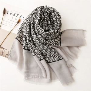 Linen cotton scarf with geometric eye patterns and frayed edges on white surface