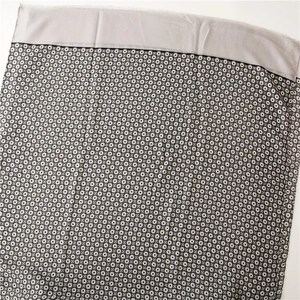 Detail of geometric circle pattern on gray silk scarf with delicate fringe edges