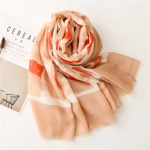 Detail of soft linen scarf with orange abstract patterns and fine fringe tassels