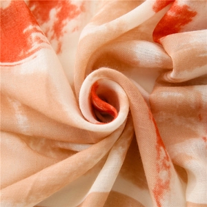 Detail of soft linen-cotton scarf with orange and beige abstract tie-dye patterns