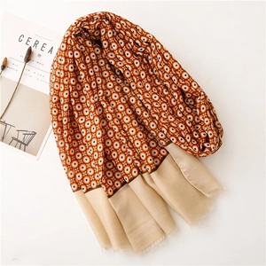 Close-up of orange patterned linen scarf with beige borders and fringe tassel details