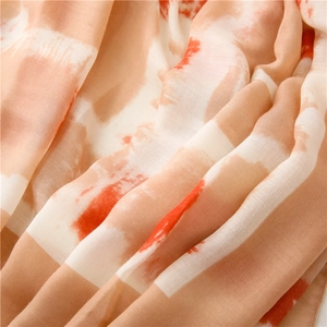 Detailed close-up of soft breathable linen cotton scarf with orange and brown geometric print