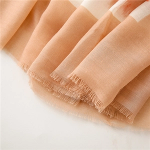 Close-up of lightweight linen shawl with orange floral patterns and delicate fringe