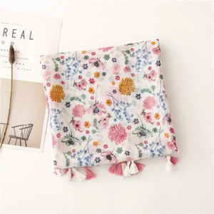 Close-up of floral print scarf with soft pastel flowers and pink fringe tassels detail