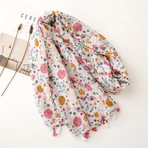 Lightweight floral print scarf with tassel trim on white background and cereal magazine