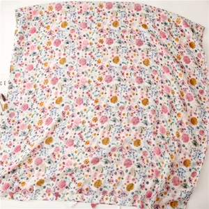 Detailed flat lay of a floral summer scarf featuring pink tassels and colorful flower prints