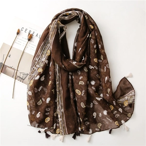 Detail of bohemian brown paisley scarf featuring delicate tassels and soft fabric texture