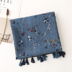 Detail of blue floral cotton linen scarf with bird patterns and fringe tassels