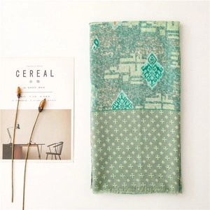 Detail of green paisley cotton scarf with ethnic geometric patterns and fringe edges