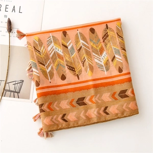 Dettaglio di scialle boho arancio-rosa con stampe piumate e bordi sfrangiati eleganti