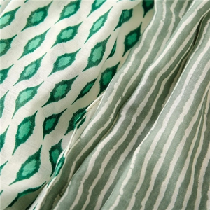 Detail of soft cotton-linen shawl featuring green geometric diamonds and wavy stripes