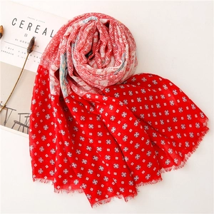 Detail of red paisley scarf with geometric patterns and fringe edges on white background