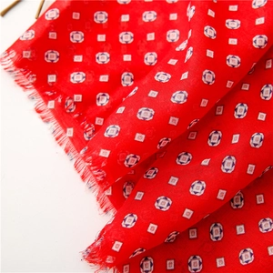 Detail of red paisley scarf showing soft cotton texture and fringed edges close-up