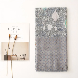 Detail of grey-blue paisley pattern scarf with fringe edges and geometric print