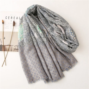 Detail of soft cotton scarf with blue paisley patterns and fringe edges on white background