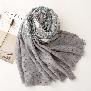 Flat lay of soft cotton scarf with striped paisley patterns and fringe edges on white desk
