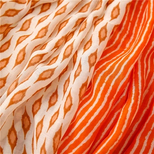 Detail of soft fabric scarf showing geometric diamond patterns and orange wave stripes
