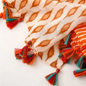 Detail of bohemian cotton linen scarf featuring orange geometric prints and colorful tassels