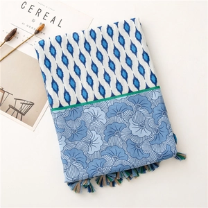 Detail of blue floral print scarf featuring geometric patterns and colorful tassel edges