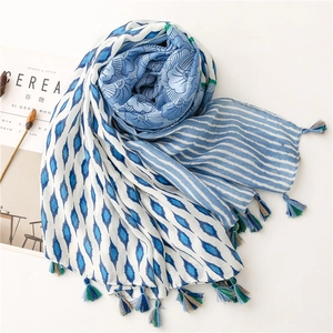 Close-up of blue and white floral scarf with mixed tassels and geometric patterns