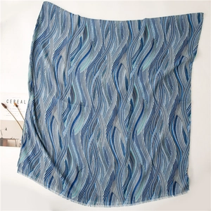 Detail eines blauen Schals mit Wellenmuster, Fransen und leichter Textur