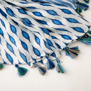 Detail of soft cotton linen scarf with blue geometric patterns and colorful tassels
