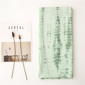 Detail of light green tie-dye scarf with soft linen texture and frayed edges on magazine
