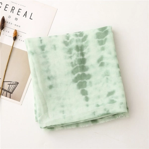 Detail of light green tie-dye scarf with soft fringe edges and linen texture