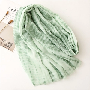 Detail of light green tie-dye cotton-linen scarf with natural frayed edges and soft texture