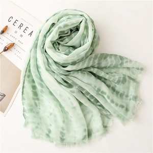 Detailed view of light green tie-dye cotton linen scarf with delicate fringed edges