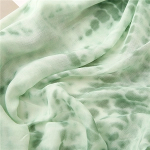 Detailed close-up of light green tie-dye cotton linen scarf with soft wrinkled texture