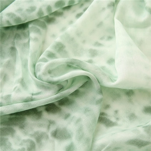 Detail shot of light green tie-dye cotton-linen fabric texture with soft draped folds