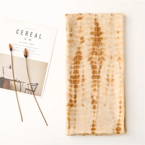 Flat lay of tie-dye beige and brown cotton linen scarf with soft wrinkled texture