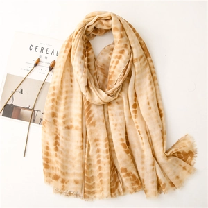 Detailed close-up of soft tie-dye linen scarf texture with elegant raw fringed edges