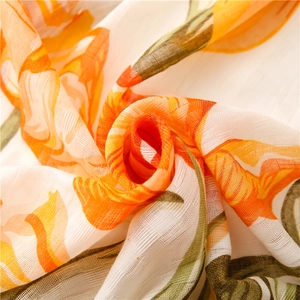 Macro shot of soft floral printed scarf fabric with orange petals and green leaves