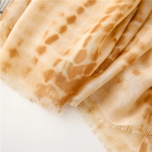 Close-up of soft cotton-linen scarf with brown tie-dye pattern and delicate fringed edges