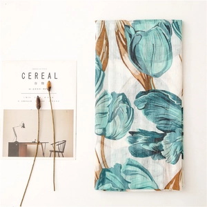 Detailed flat lay of floral cotton linen shawl with green tulips next to a magazine