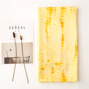 Detail of yellow tie-dye cotton linen scarf with frayed edges and soft texture