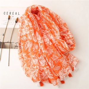 Floral print orange shawl with sequins and fringe detail on minimalist lifestyle background