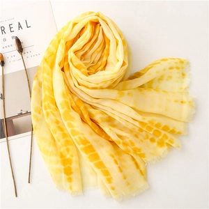 Artistic yellow tie-dye scarf detail featuring fine fringe edges and soft cotton-linen texture