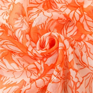 Macro detail of orange floral print on sheer fabric with shimmering sequins embroidery