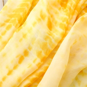 Macro shot of vibrant yellow tie-dye fabric with soft gradient and light texture