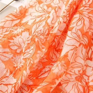 Detail of orange floral fabric with silver sequins and lightweight breathable texture