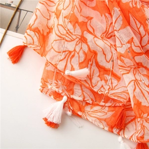Detail of orange floral print scarf with sparkling sequins and bicolor fringed tassels