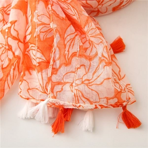 Detail of orange floral scarf featuring sequins, metallic threads and bicolor fringe tassels