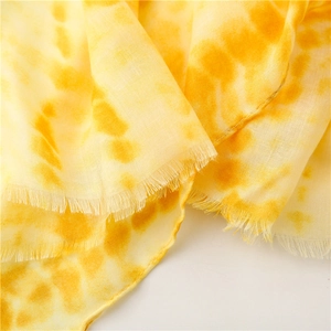 Macro view of breathable tie-dye cotton-linen scarf with raw edges and yellow ombre texture
