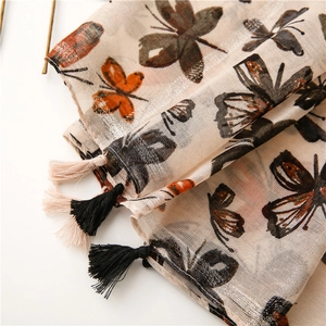 Vue macro de l'imprimé papillon et des pompons sur une écharpe vintage beige