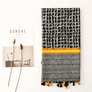 Detail view of vintage geometric grid scarf with yellow stripes and tassel trim